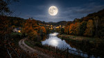 Full moon over an autumn village and reflective river